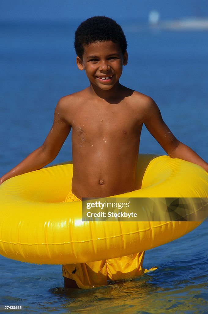 A young boy (5-7) holding an inflatable ring and smiling