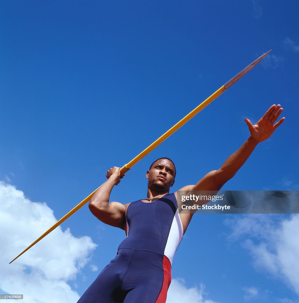 Low angle view of a young male athlete with a javelin