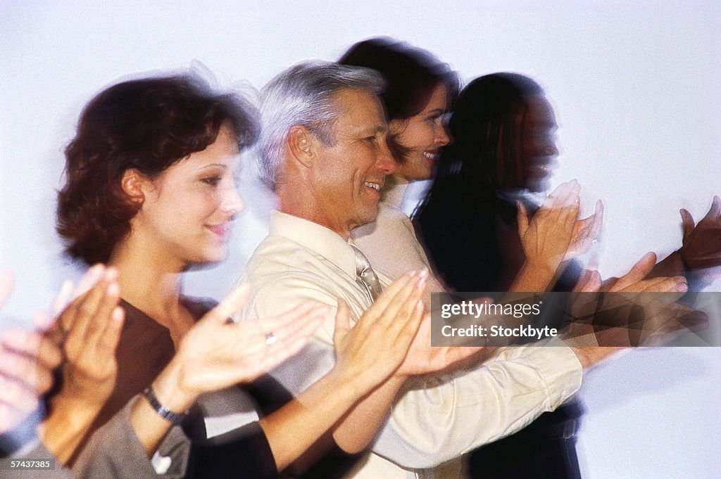 Blurred side profile of men and women standing and clapping