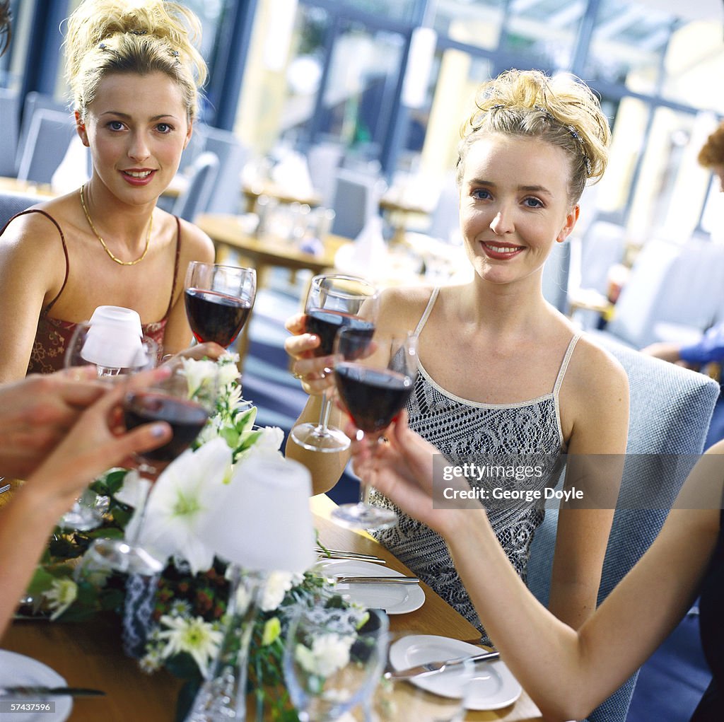 Portrait of a group of young women toasting with red wine