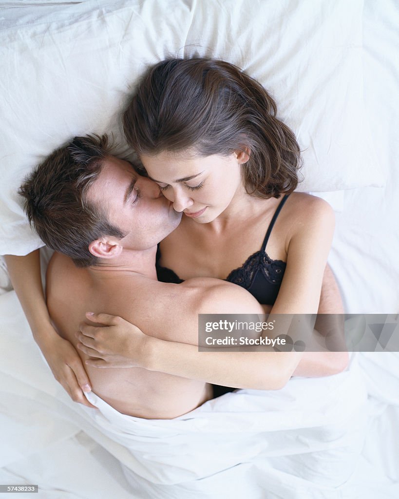 Elevated view of a young couple holding each other in bed