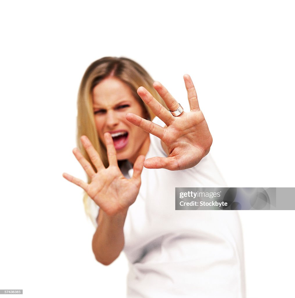 Portrait of a young woman with her arms raised palms showing in fear