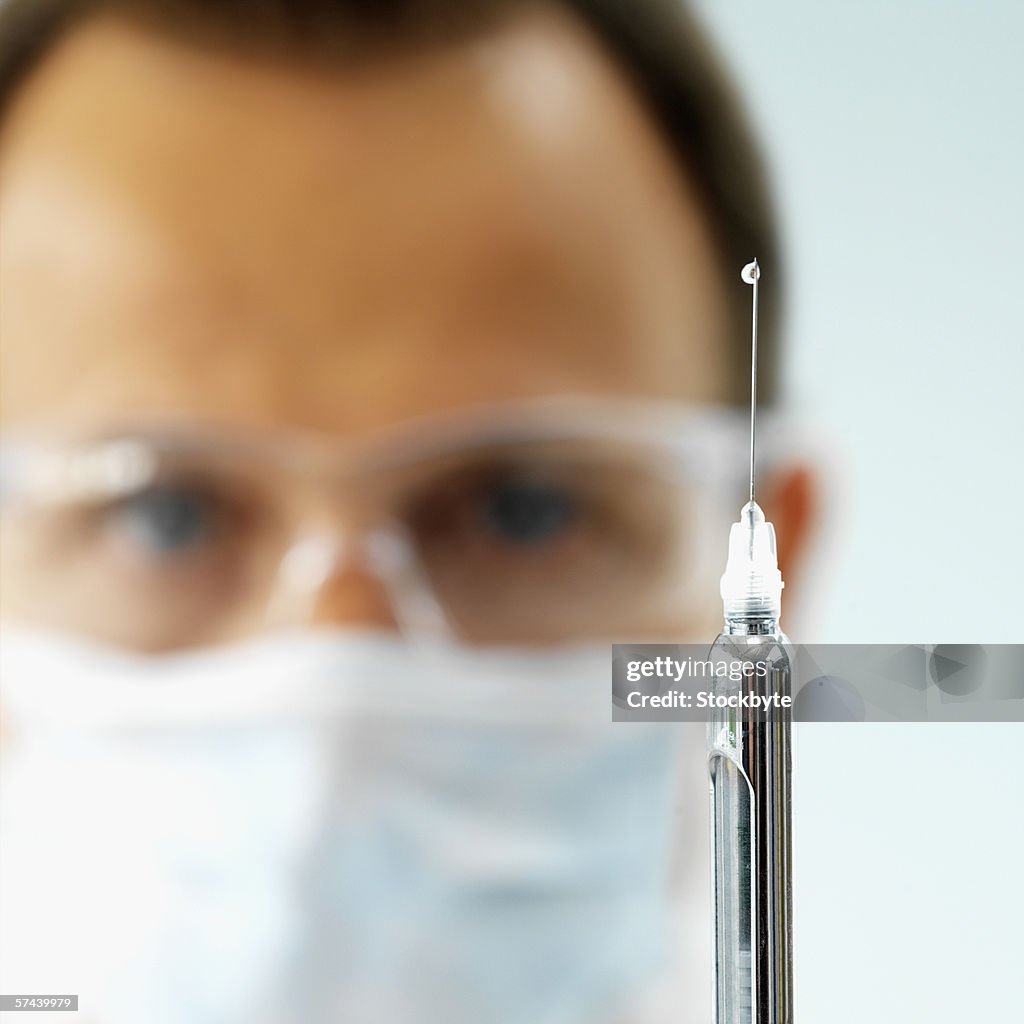 Close up of a syringe held by a dentist