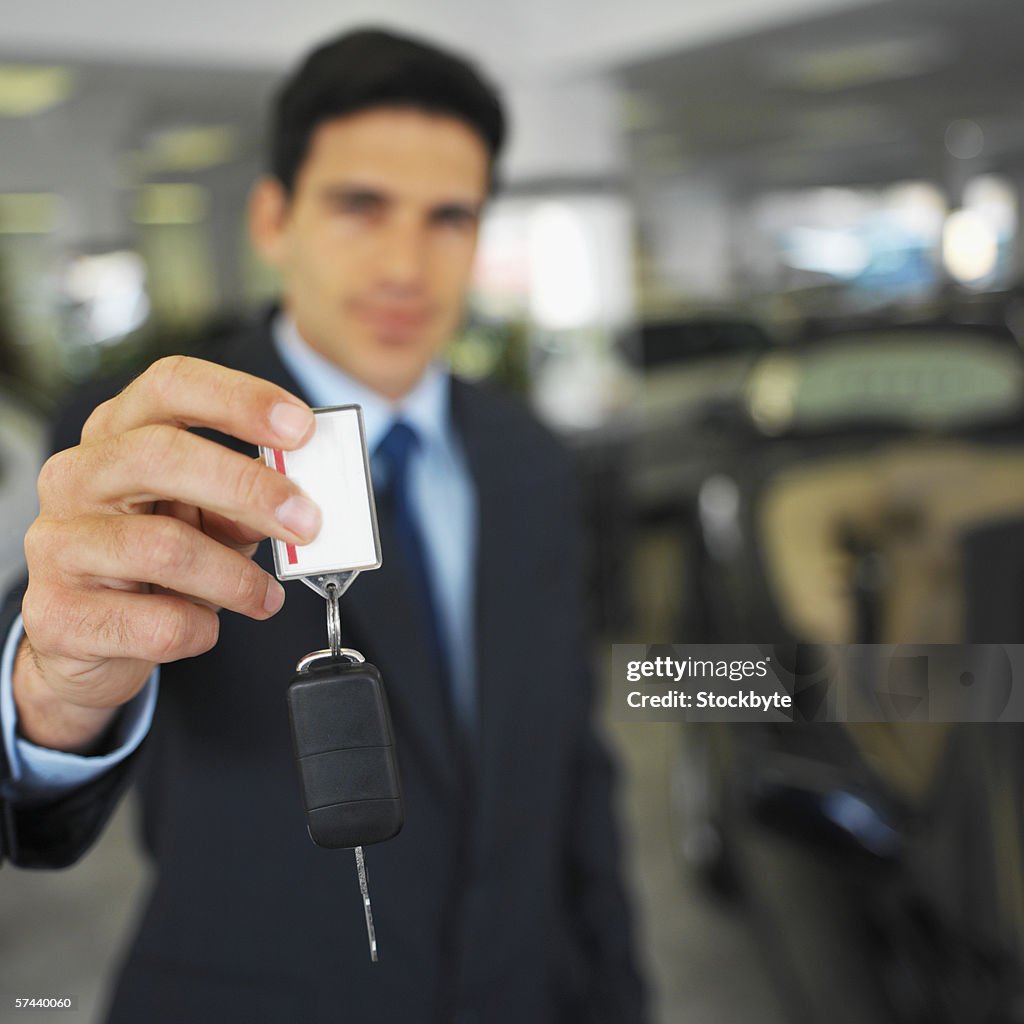 Portrait of a salesman holding out a car key