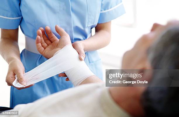 female nurse dressing a man's hand - applying bandage stock pictures, royalty-free photos & images