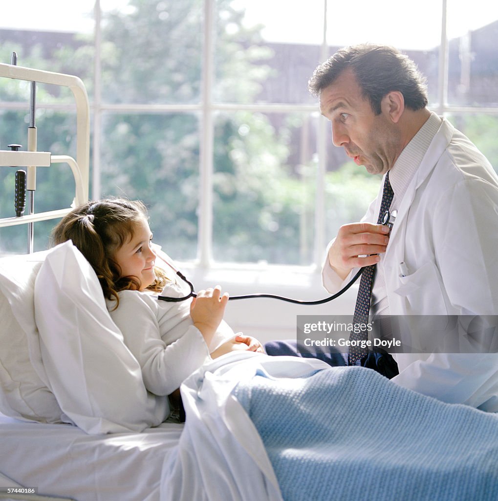 Portrait of a young girl using a stethoscope on her doctor