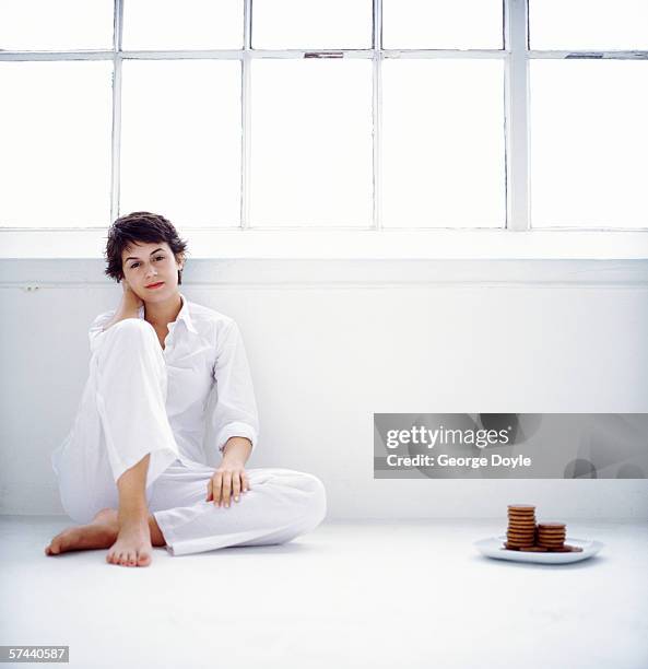 portrait of a woman sitting on the floor beside a plate of cookies - picky eater stock pictures, royalty-free photos & images