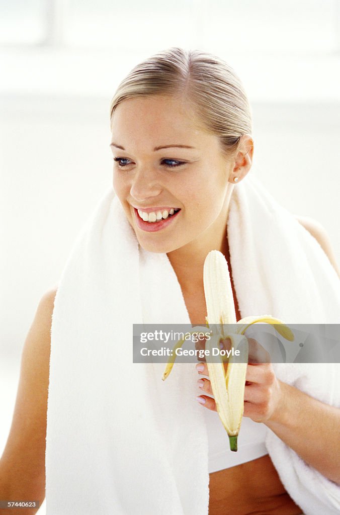 Close-up of a woman wearing a sweat towel and holding a peeled banana