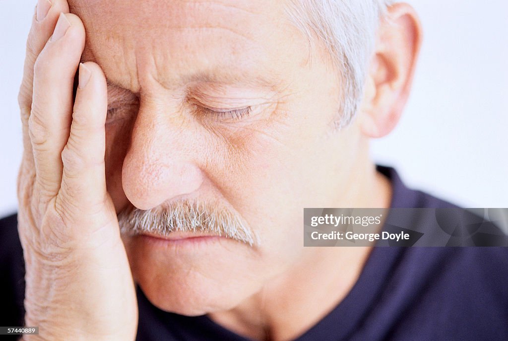 Close-up of a man holding the side of his face