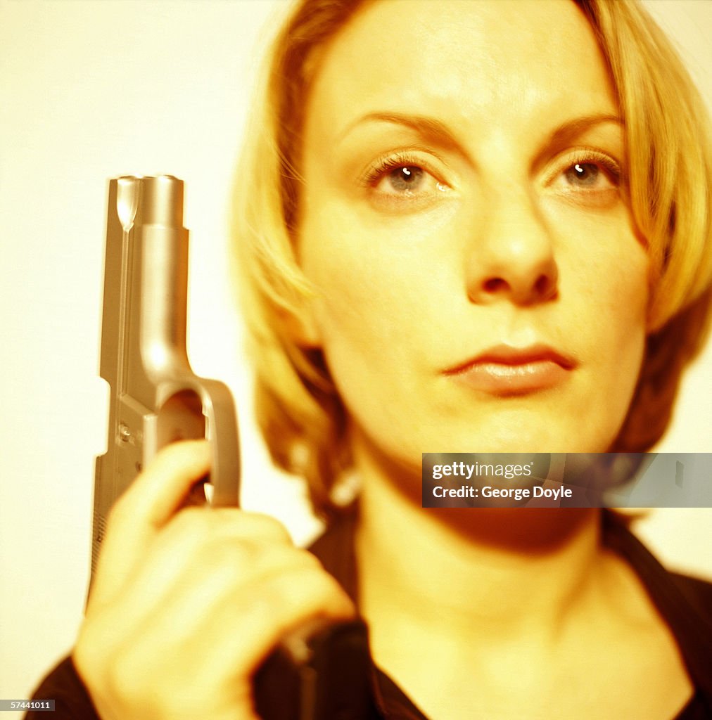 Close-up young woman holding a pistol