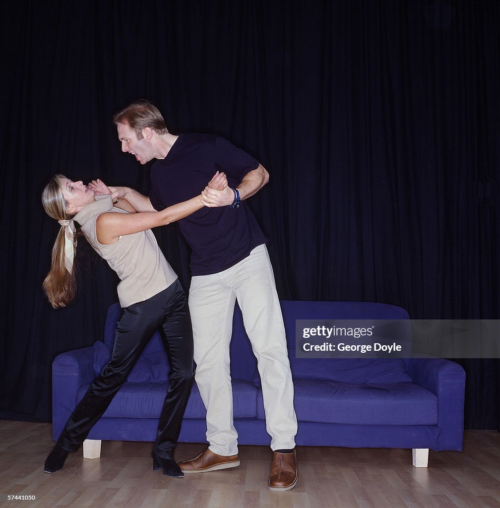 Angry husband holding a frightened wife by her collar