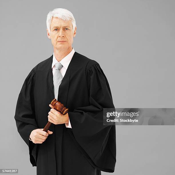 portrait of a male judge, holding a gavel - judge robe stock pictures, royalty-free photos & images