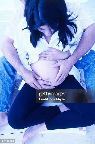 high angle view of a man holding his pregnant wife's stomach from behind - male belly button stock pictures, royalty-free photos & images