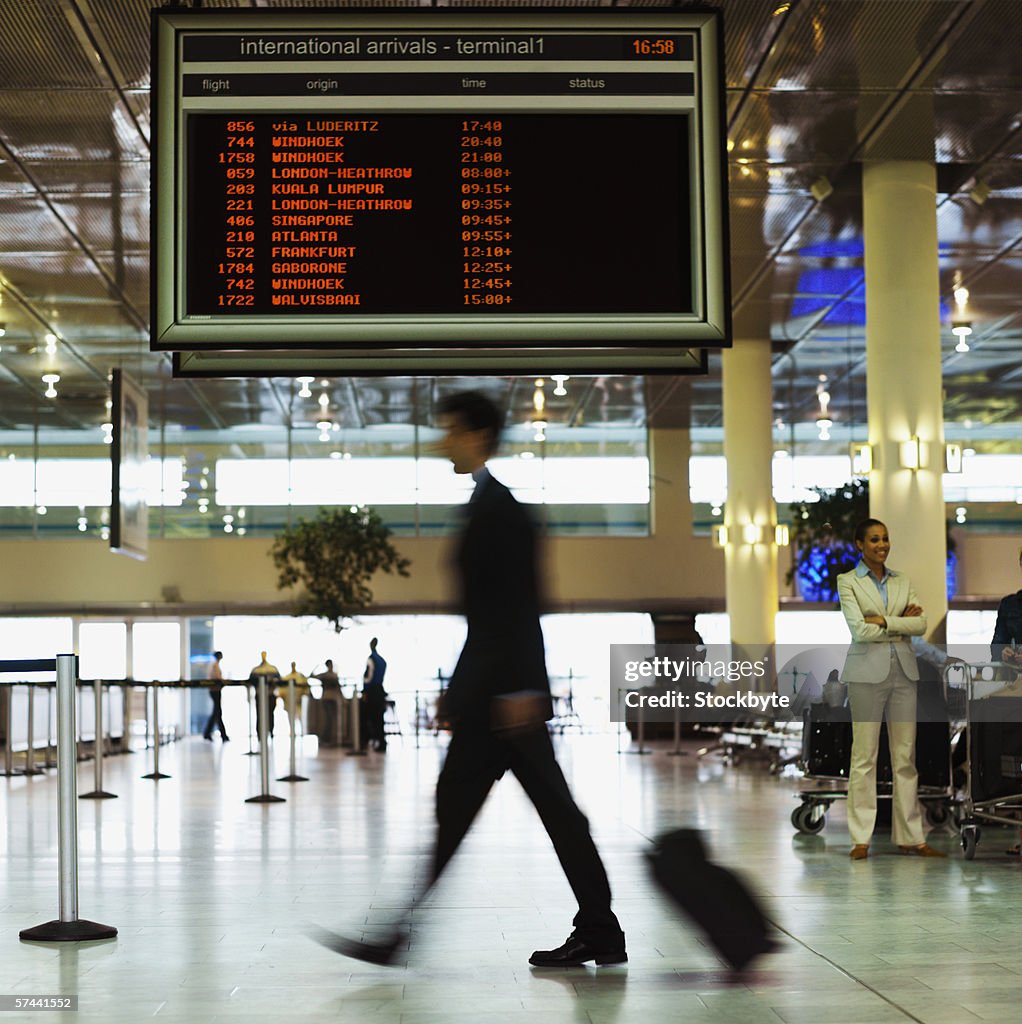 Businessman walking past an information board at an airport