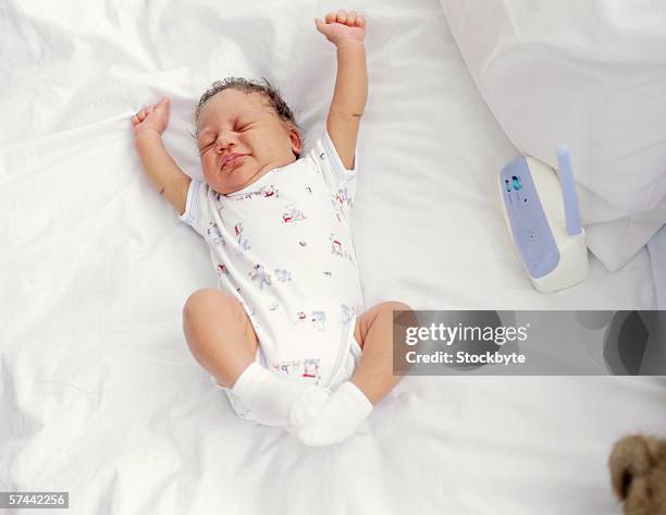 high angle view of a baby stretching on a bed - babyphone stock-fotos und bilder