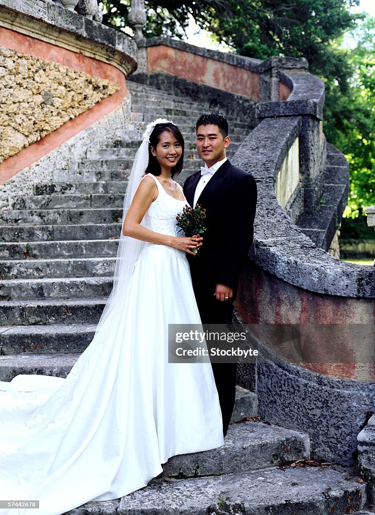 Portrait of a bride and groom standing at the bottom of steps