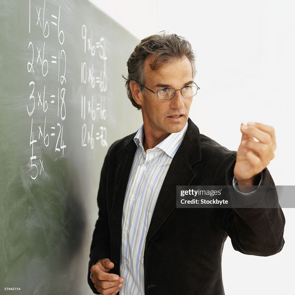 Male school teacher looking at a piece of chalk