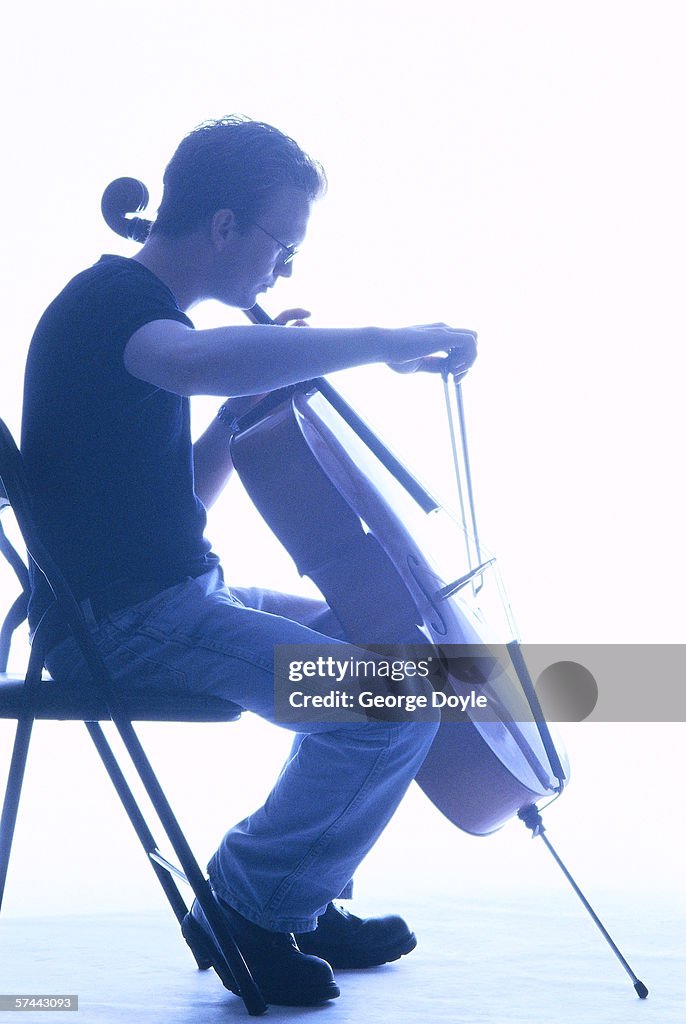 Shot of a man sitting down and playing the cello