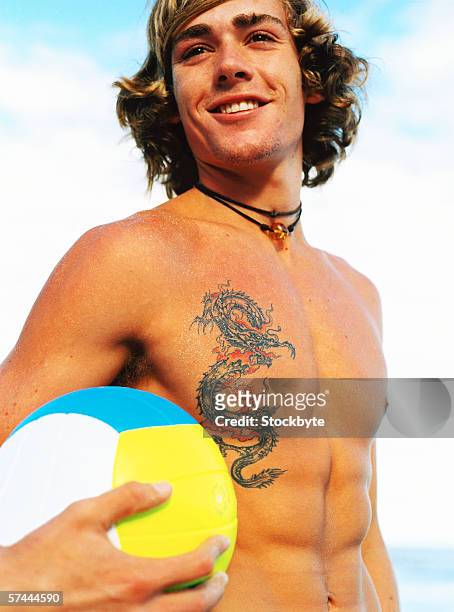a young man standing holding a volleyball - white dragon tattoo stock pictures, royalty-free photos & images