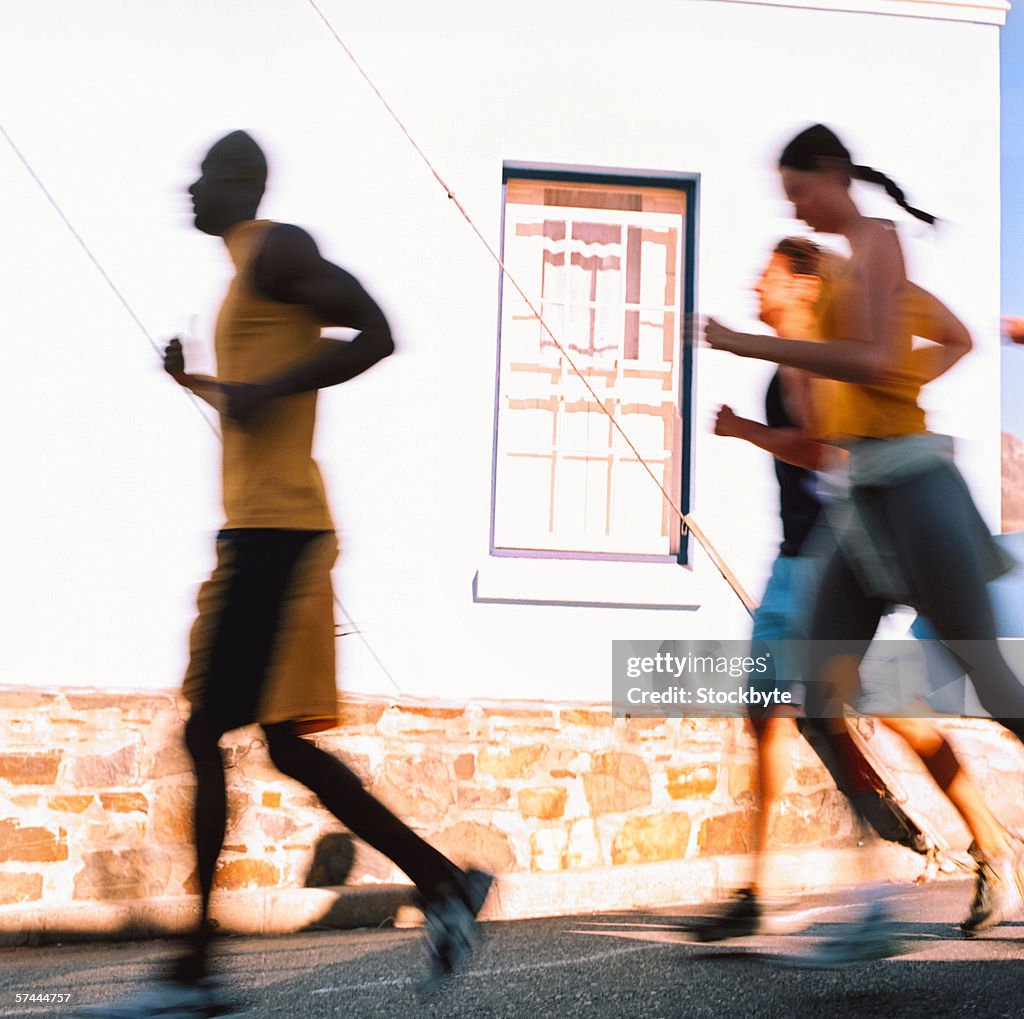 Blurred side profile of a group of people jogging outdoors