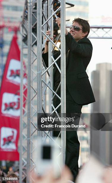 American actor Tom Cruise climbs a scaffolding to wave to the crowd after arriving at the "Mission: Impossible III" French Premiere on April 26, 2006...