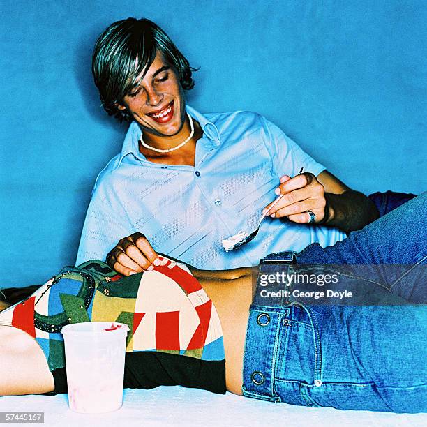 a young man putting a spoon of whip cream on to a woman's belly button - male belly button 個照片及圖片檔