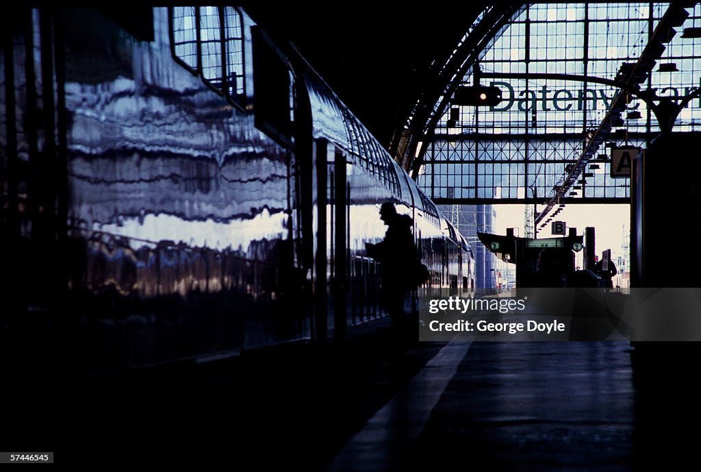 Silhouette of a man stepping into a train from a station