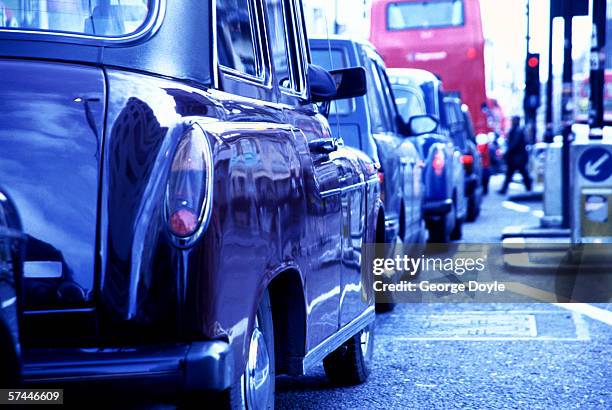 low angle close-up of cars from behind parked at a red light junction - london traffic stock pictures, royalty-free photos & images