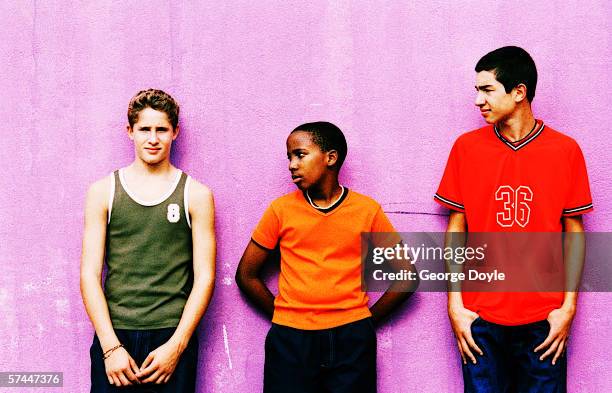 view of three teenaged boys standing against a wall - boy jeans stockfoto's en -beelden