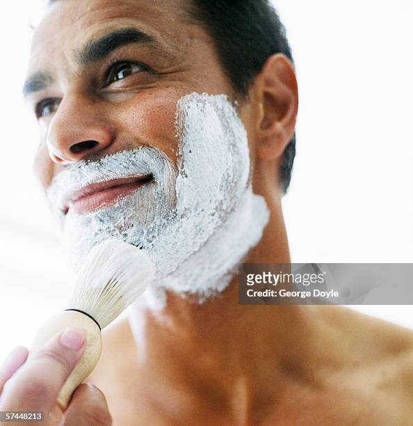 close-up of man lathering shaving cream on his face with a brush - shaving brush stock-fotos und bilder