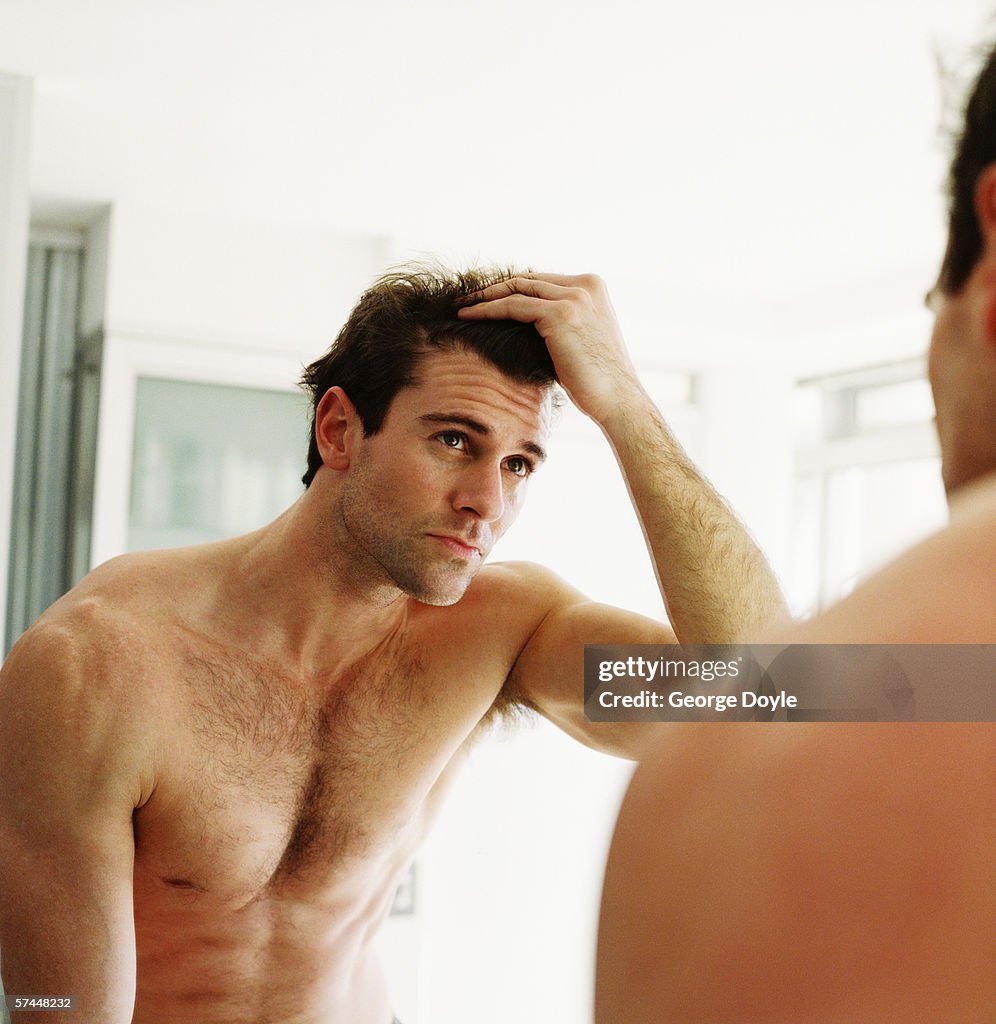 Close-up of a man checking his hair in the mirror