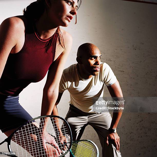 low angle close-up of a couple playing a mixed doubles game of tennis - racketball stock pictures, royalty-free photos & images