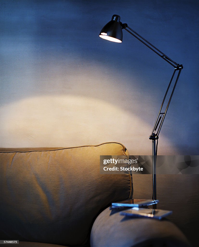 Close-up of a sleek metal lamp lying on the armrest of a couch