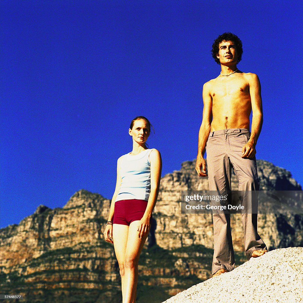 Low angle view of a young couple standing on a rock in the wilderness