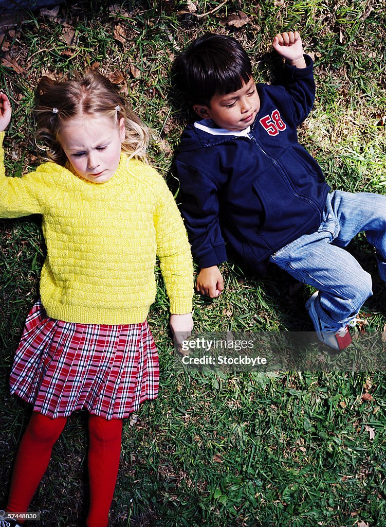 Elevated view of two young children (4-8) lying on the grass