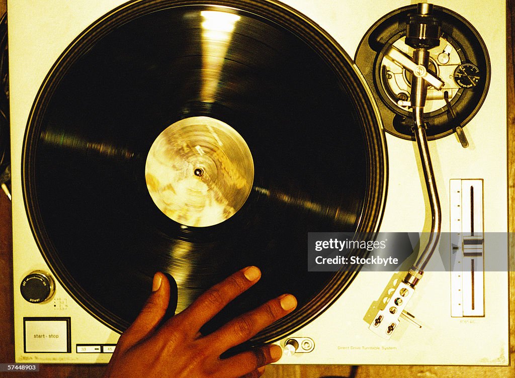 High angle close-up of a hand scratching a vinyl record on a turntable