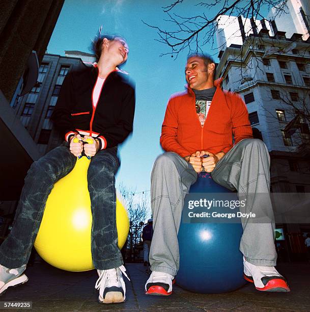 low angle view of a couple bouncing on rubber balls on a street - homme en contre plongée fait le pitre photos et images de collection