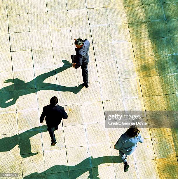 high angle view from behind of three businessmen running out of a building - antenna aerial stock pictures, royalty-free photos & images