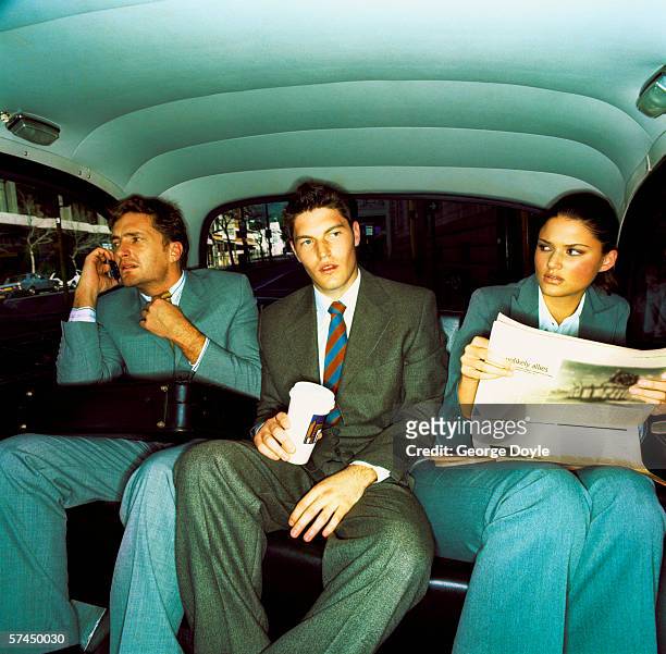 three co-workers sitting in the backseat of a car; waiting - man in car reading newspaper stock pictures, royalty-free photos & images