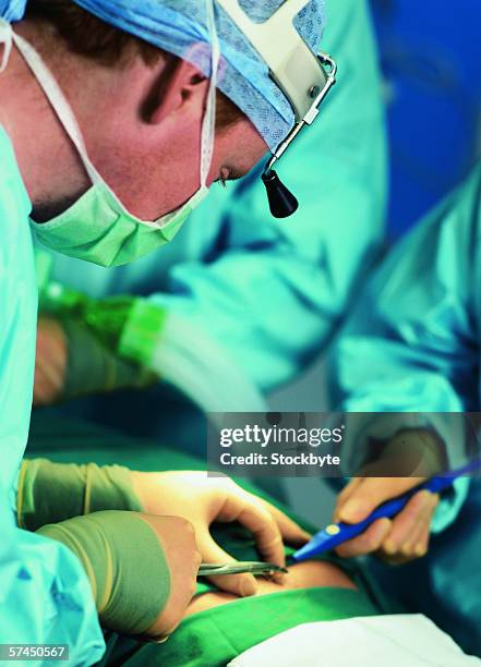 side profile of a surgeon performing a surgical procedure - surgical mask profile stock pictures, royalty-free photos & images