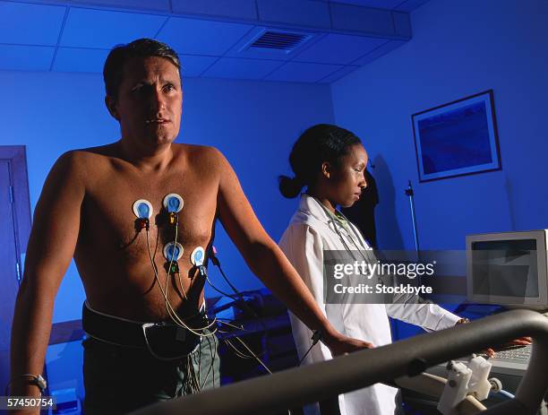 a female doctor performing a stress test on a man - belastungsprobe stock-fotos und bilder