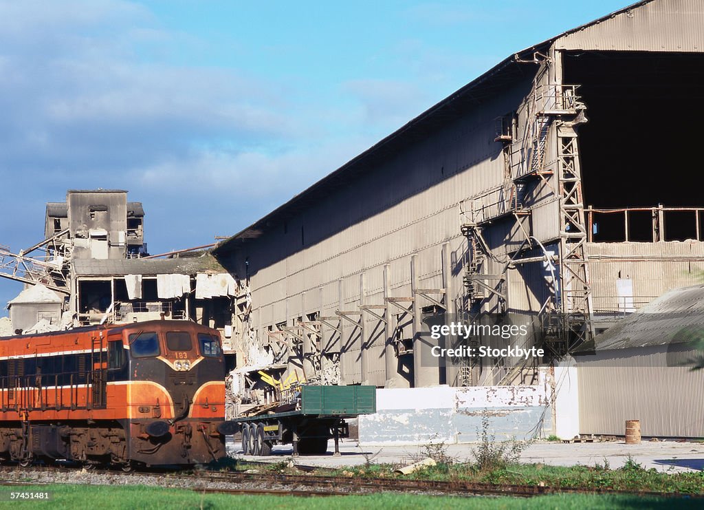 View of a train going past an industrial warehouse