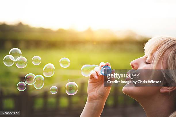 young woman blowing bubbles - bubble wand photos et images de collection