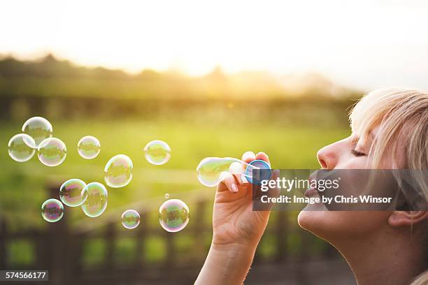 young woman blowing bubbles - bubble wand foto e immagini stock