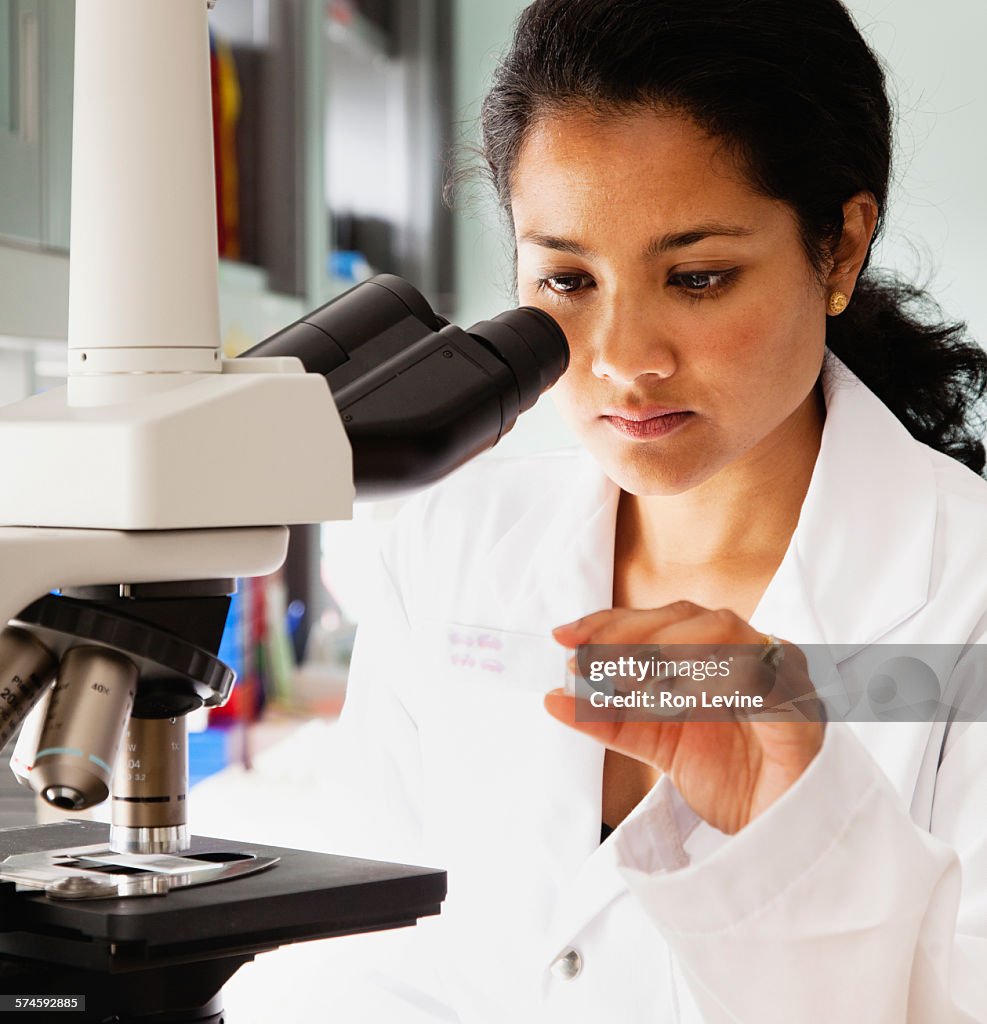 Medical technician in laboratory using microscope