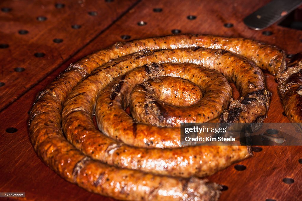 Greasy sausage on wood block serving tray