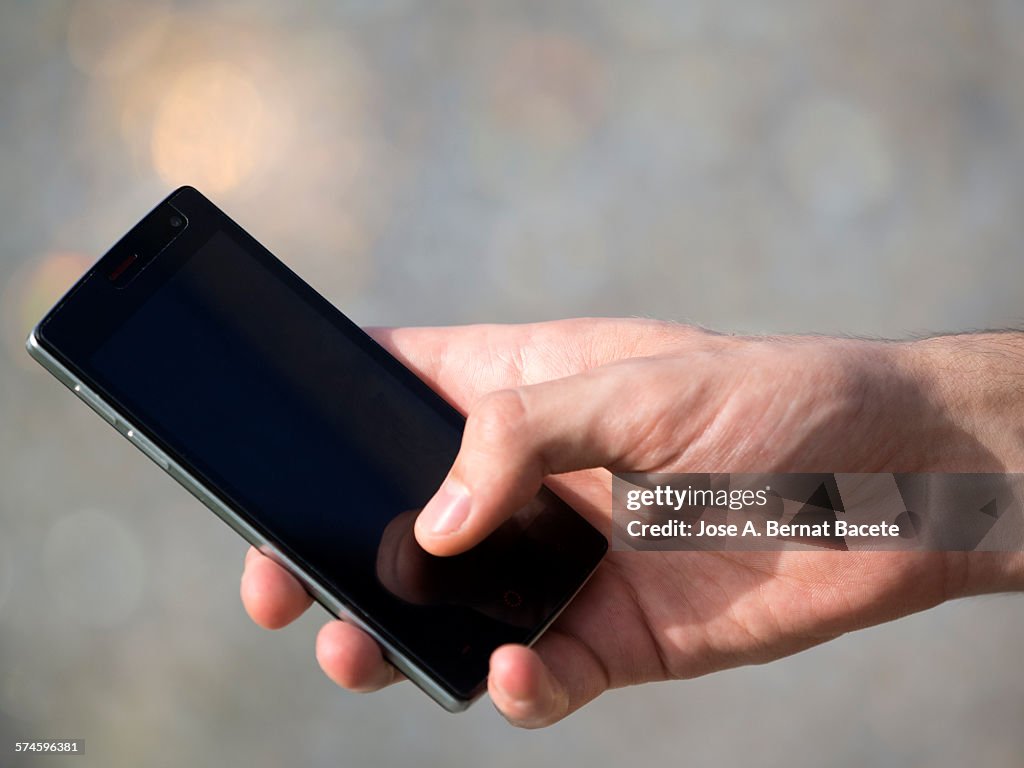 A man's hand with a mobile phone.