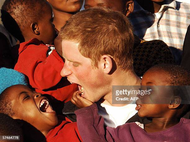 Britain's Prince Harry plays with children Mutsu and Lintle in the grounds of the Mants'ase children's home, 24 April 2006, while on a return visit...