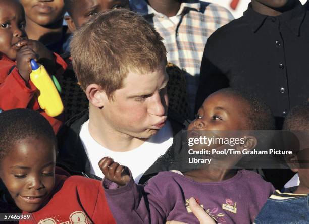 Prince Harry cuddles children Mutsu and Lintle in the grounds of the Mants'ase children's home, while on a return visit to Lesotho in southern Africa...