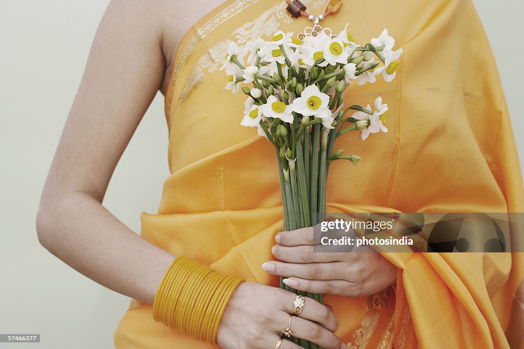 Mid section view of a young woman holding flowers